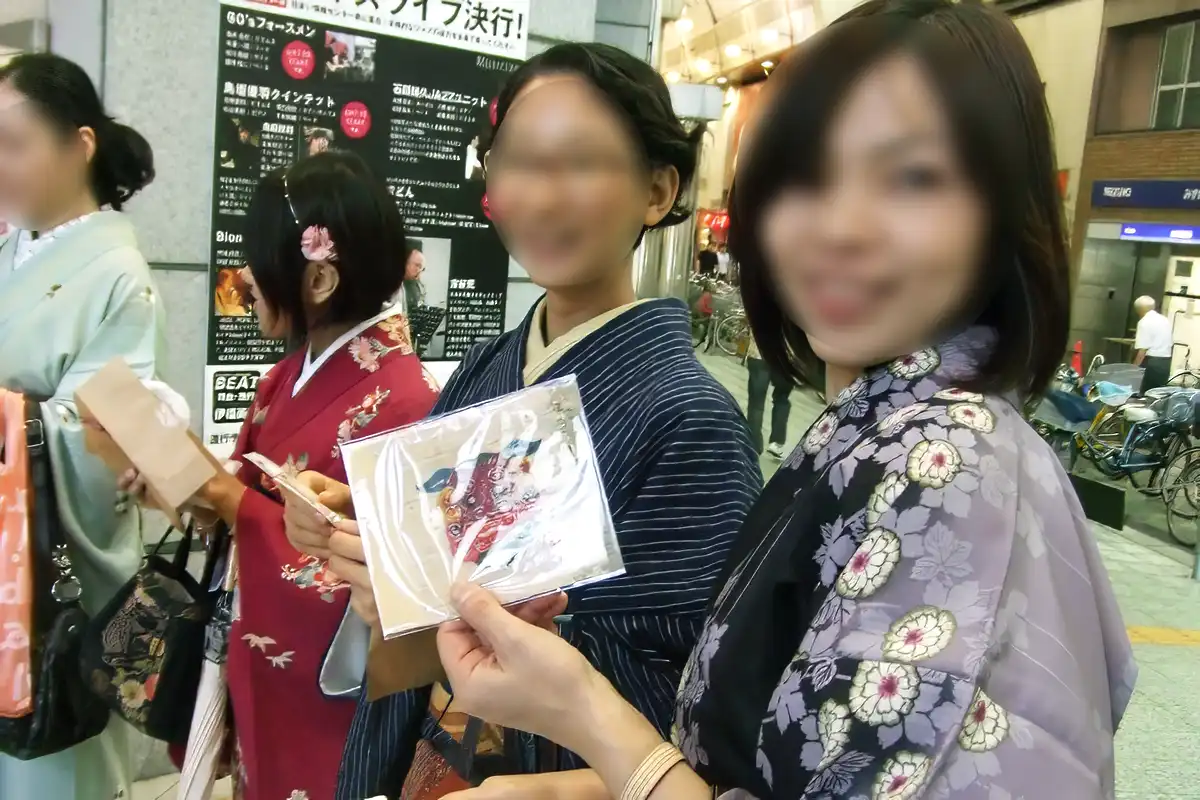 プレゼント交換でもらった品を手にする着物姿の参加者