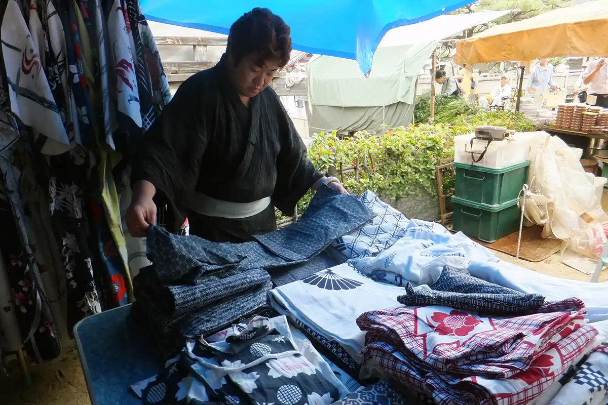 四天王寺骨董市の露店でリサイクル着物を広げる男性参加者