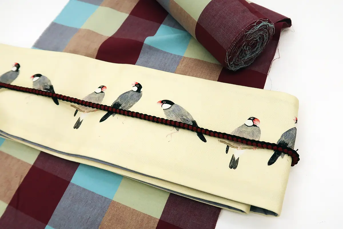 マルチカラーの伊勢木綿に鳥が描かれたベージュの半幅帯を合わせたコーディネート