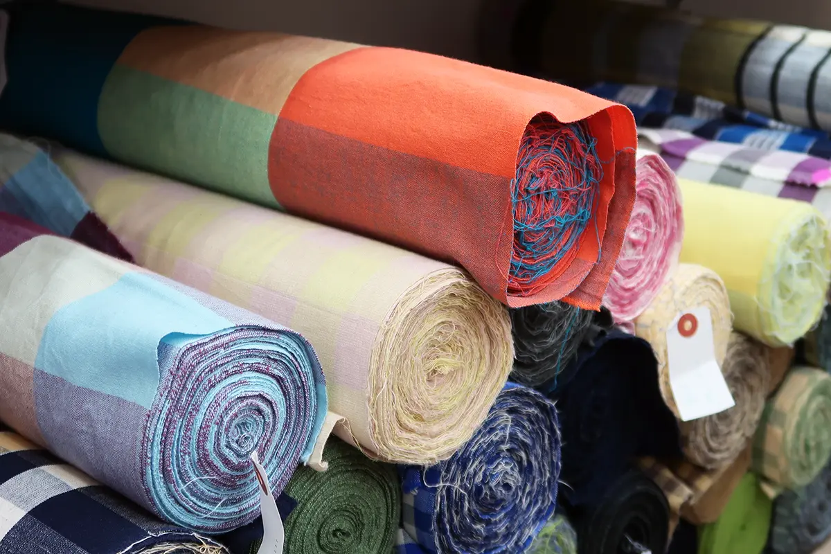 display.webp	ゴフクヤサンドットコム居内商店の店内に山積みされたカラフルな伊勢木綿の反物
