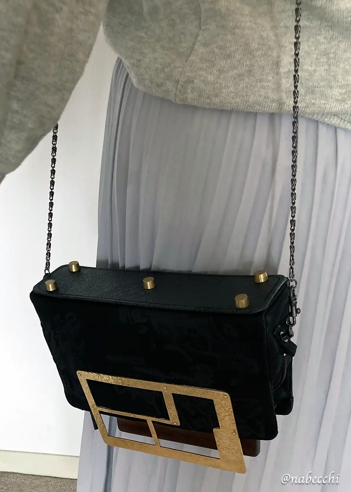 黒のチェーンストラップで肩掛けした帯バッグの着用イメージ