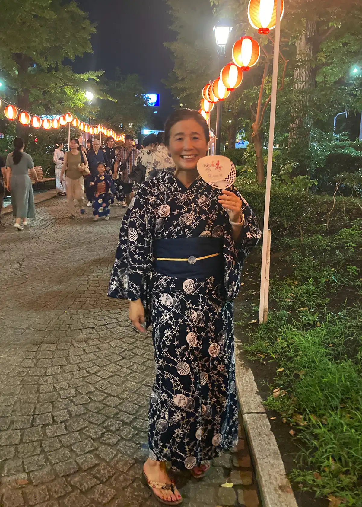 盆踊りで紺地のうちわ柄浴衣に紺色の麻半幅帯を合わせた着姿