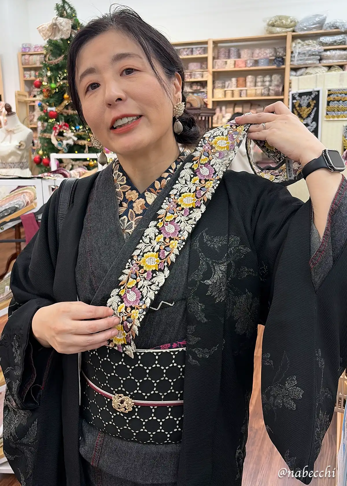 黒デニム着物にリボン半衿を合わせた筆者が、店頭で新しいリボンを襟元に当てて検討している様子。