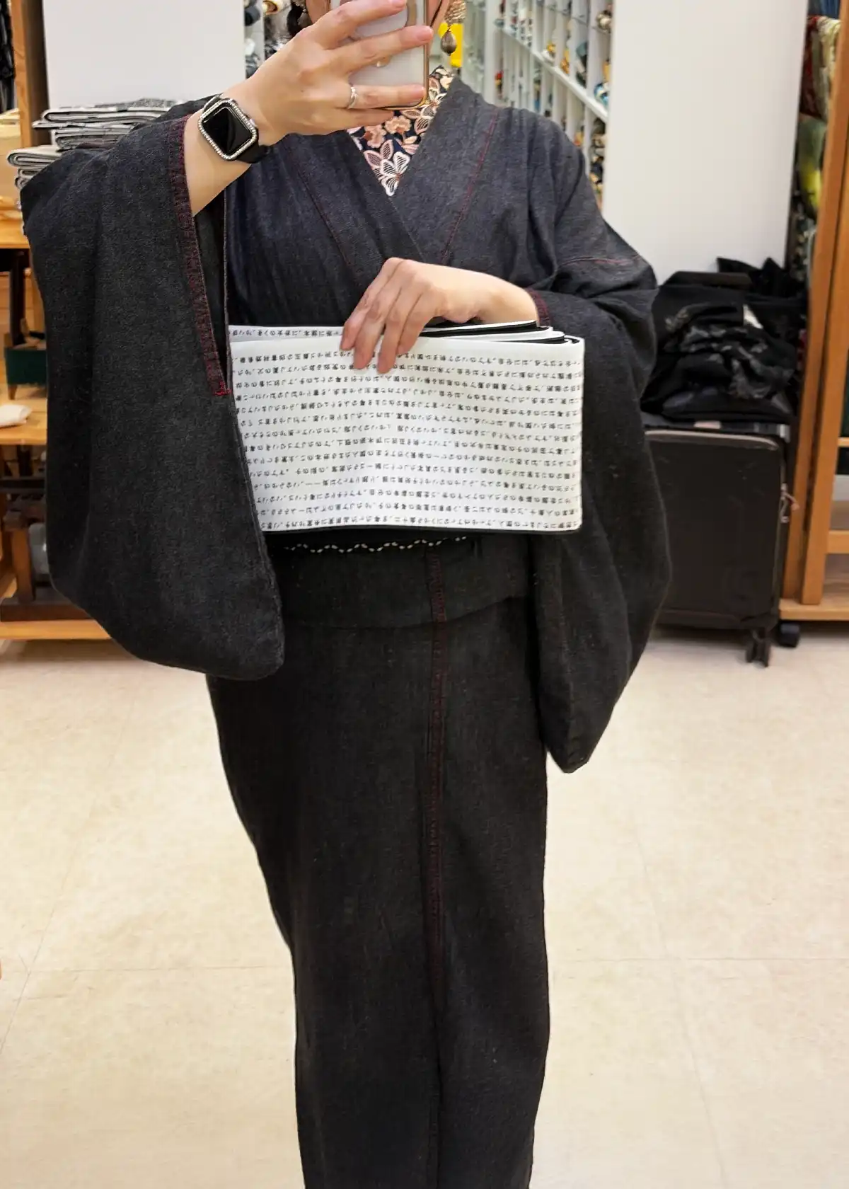黒デニム着物を着た筆者が、店員さん提案のモノトーン半幅帯を鏡の前で体に当ててチェックしている様子。