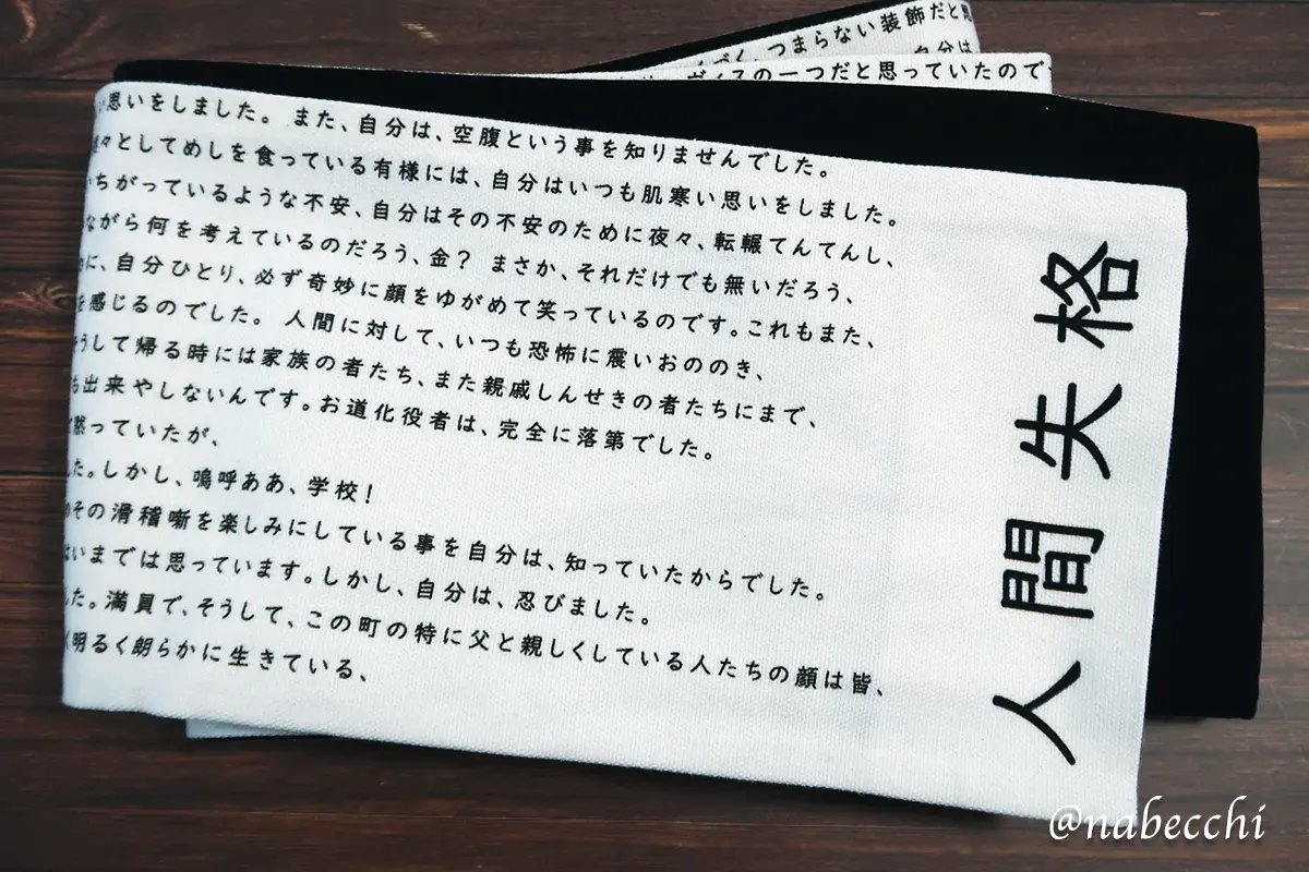 太宰治「人間失格」の本文がプリントされた帯のアップ。日本語のタイポグラフィがデザインとして映える一本。
