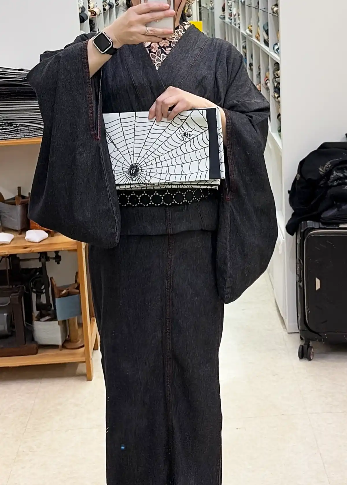 蜘蛛の巣がデザインされたエッジの効いた帯を鏡の前で合わせ、モノトーンコーデの雰囲気をチェック。