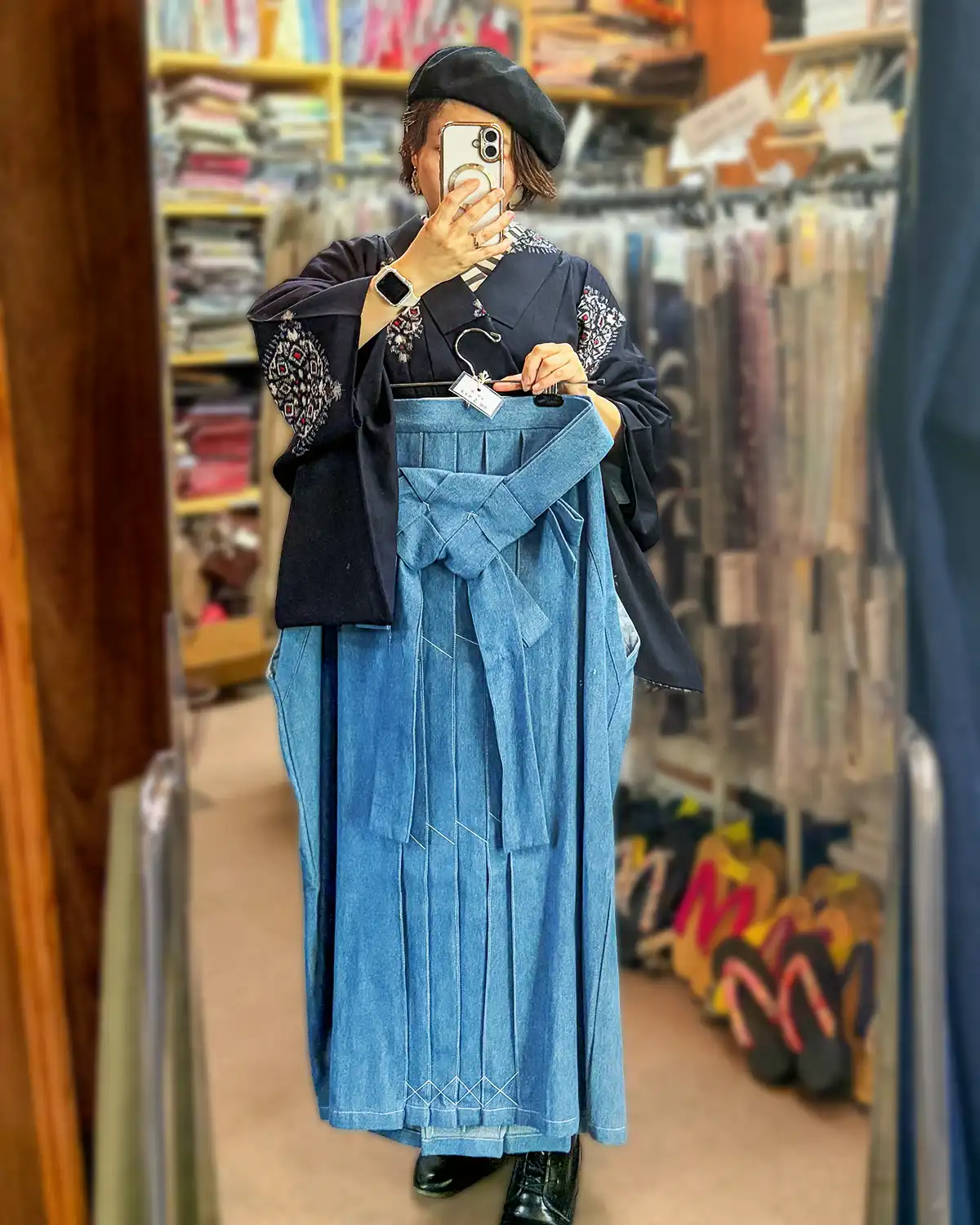 鏡の前でブルーのデニム袴を体に当てて合わせている女性