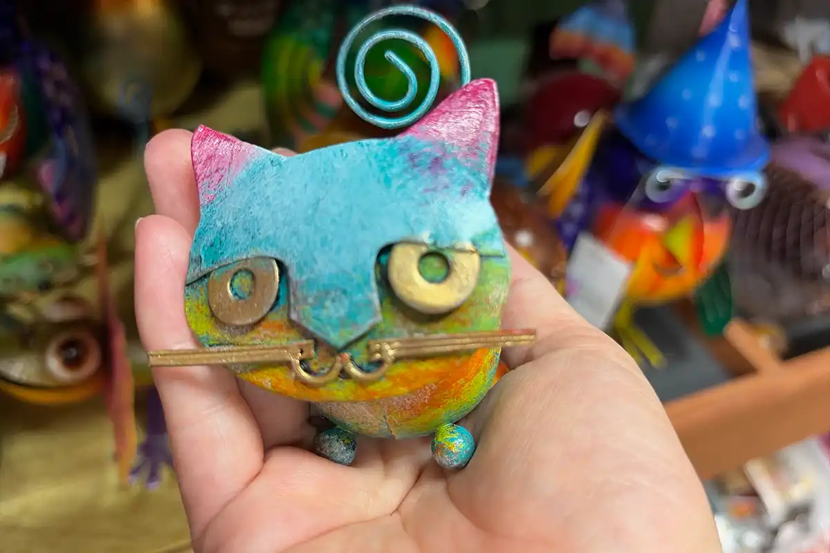 手のひらに乗せたカラフルな猫のブリキのオブジェ