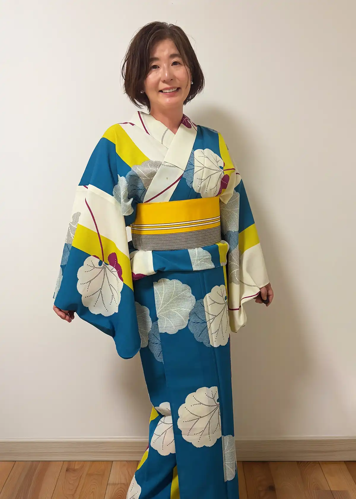 撫松庵の浴衣(白地に青・黄・紫の蓮柄)を着た女性の全身写真