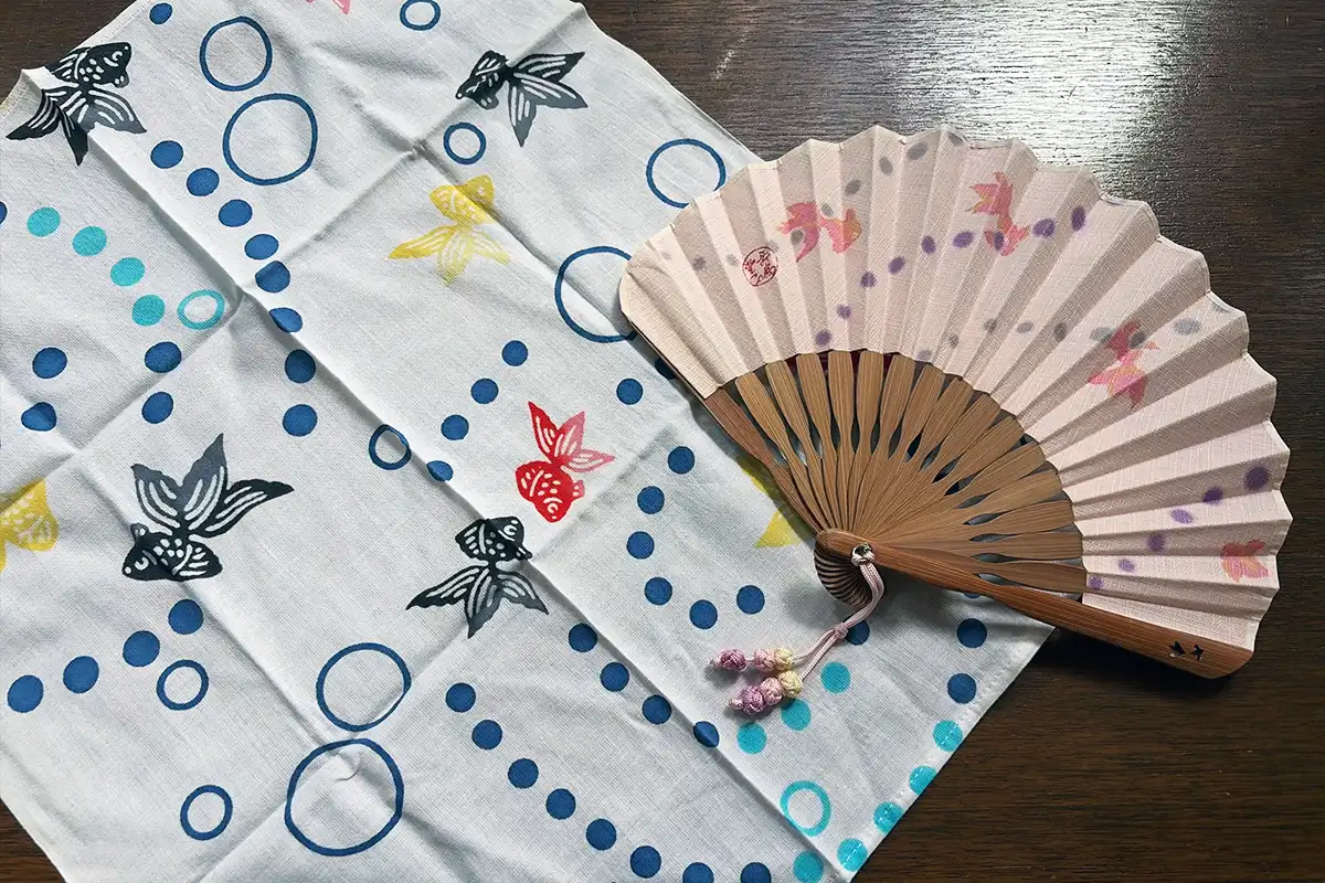 淡いピンクの金魚柄扇子とWAFUKAの金魚手ぬぐい